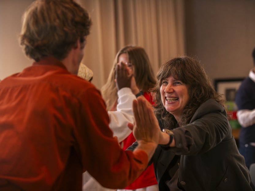 Pairs of people stand in a room palm to palm, pushing against each other.